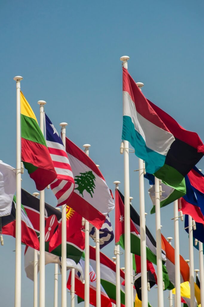 A vibrant array of international flags waving against a clear blue sky, symbolizing global unity.